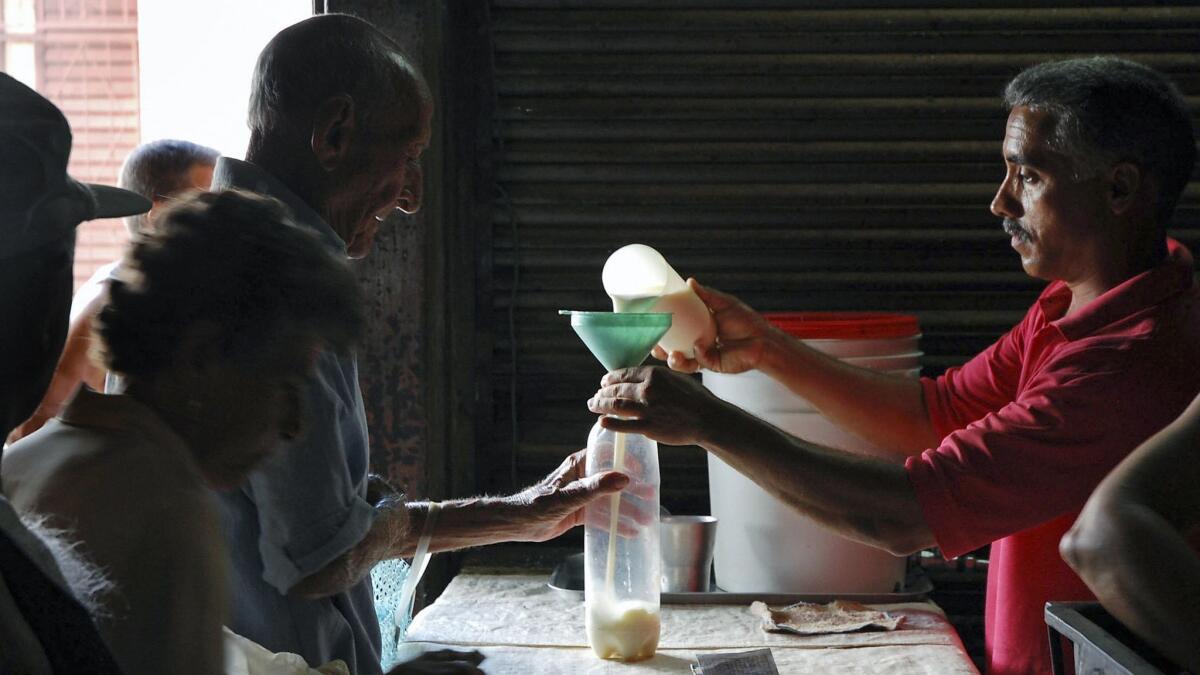 Milk is measured out for a customer at a Havana market.