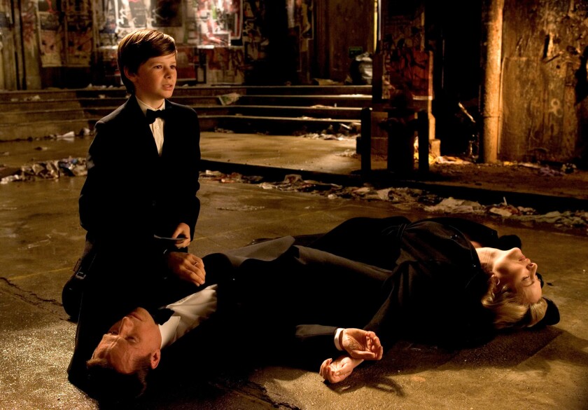 Bruce Wayne's ouders sterven in Batman Begins. Gus Lewis is de jonge Bruce Wayne, Lunus Roache is Thomas Wayne en Sara Stewart is Martha Wayne.