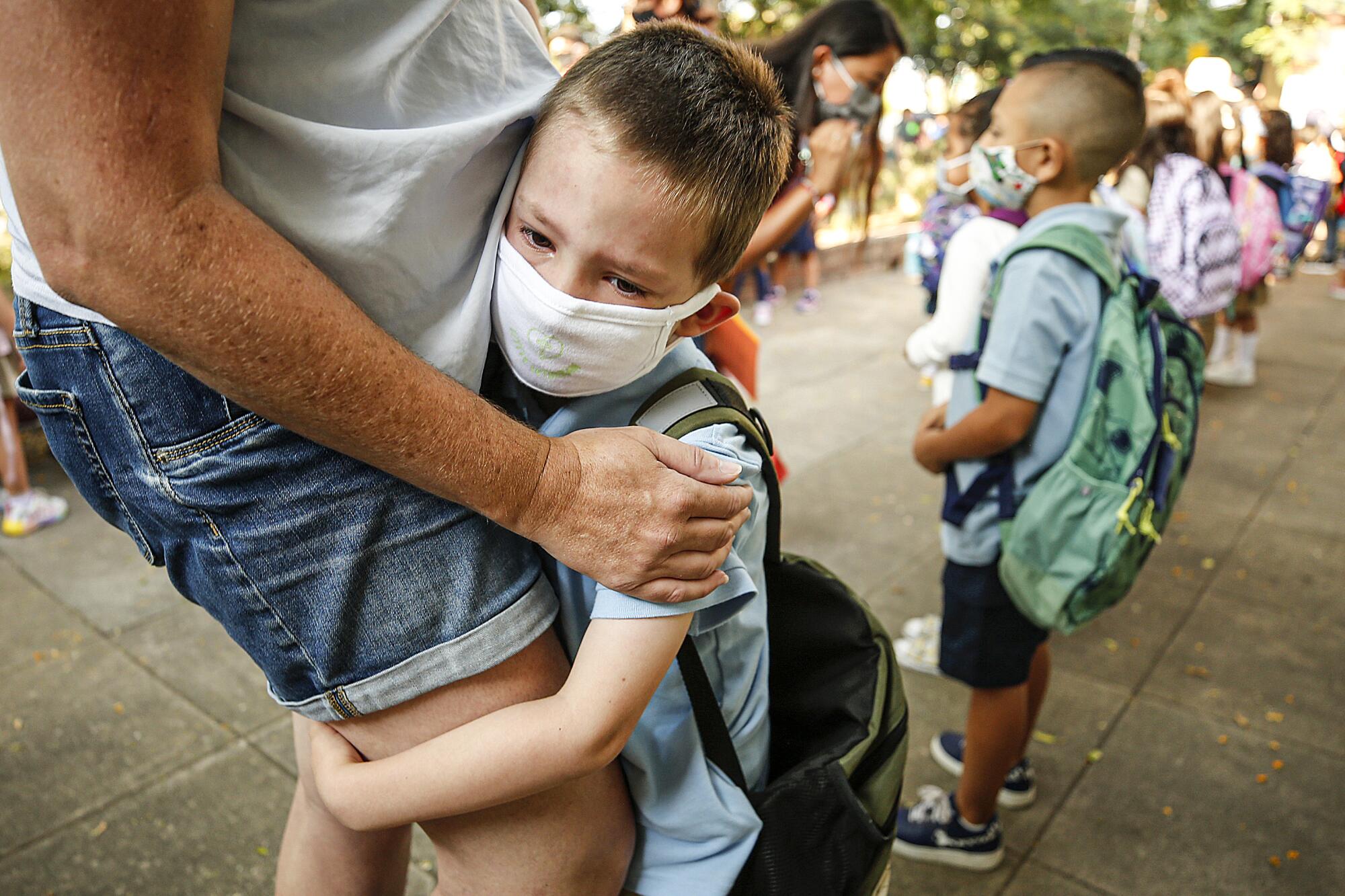 Kindergarten student August Russell clings to his Mother Natalie Russell as she tries to comfort him.