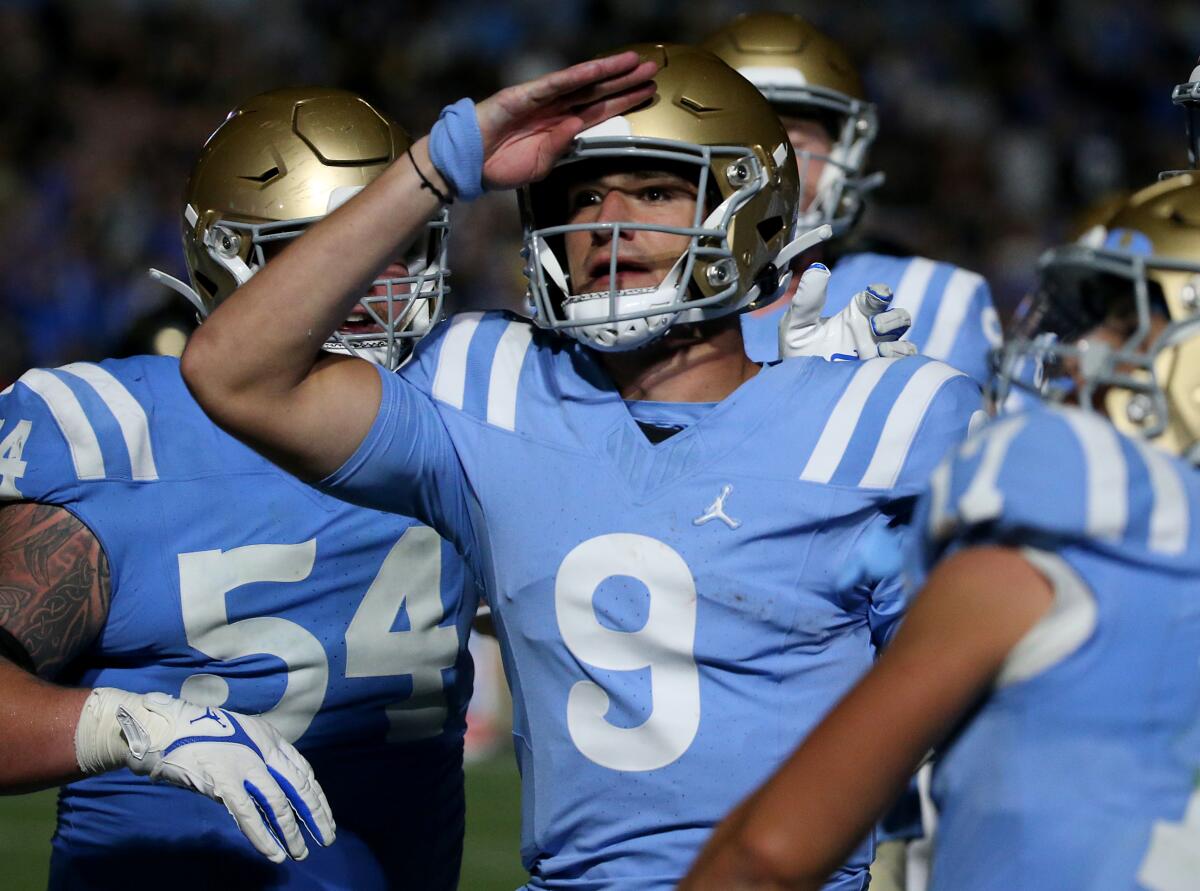 UCLA quarterback Collin Schlee salutes while celebrating after scoring a touchdown.