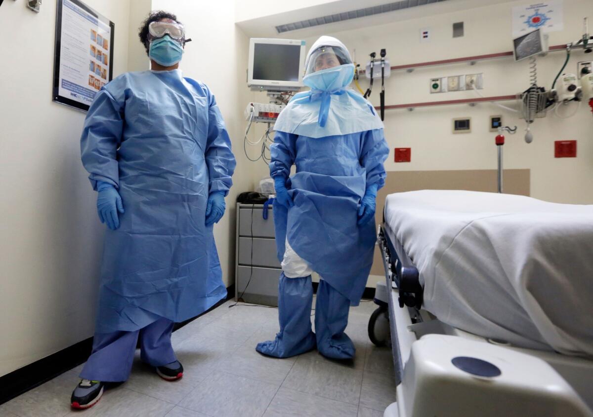 Bellevue Hospital nurse Belkys Fortune, left, and Teressa Celia, associate director of infection prevention and control, pose in protective suits in an isolation room in the New York City hospital's emergency room on Oct. 8.