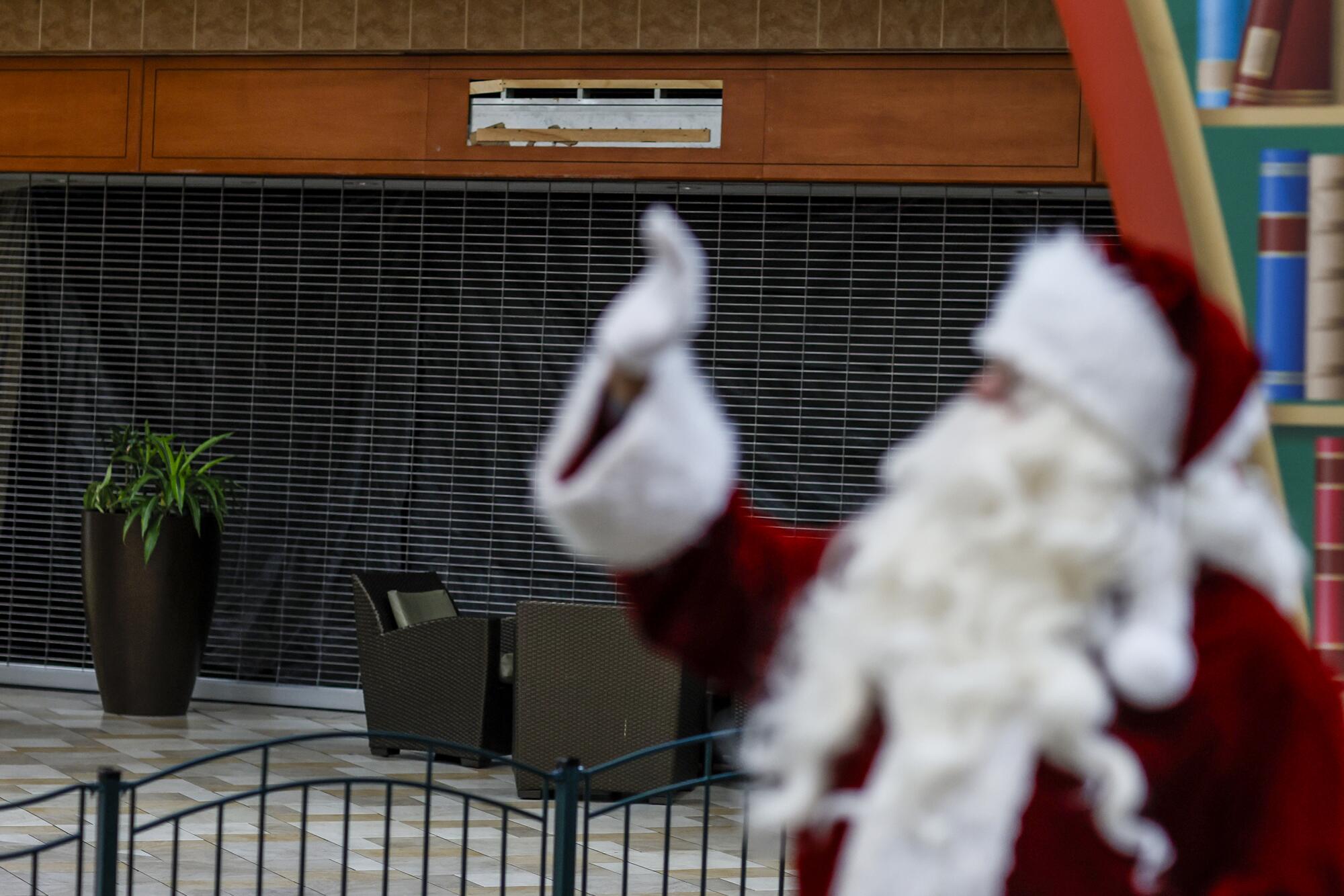 Santa, a.k.a. Albert Sanchez, waves at children across from one of many shuttered stores at the Puente Hills Mall.