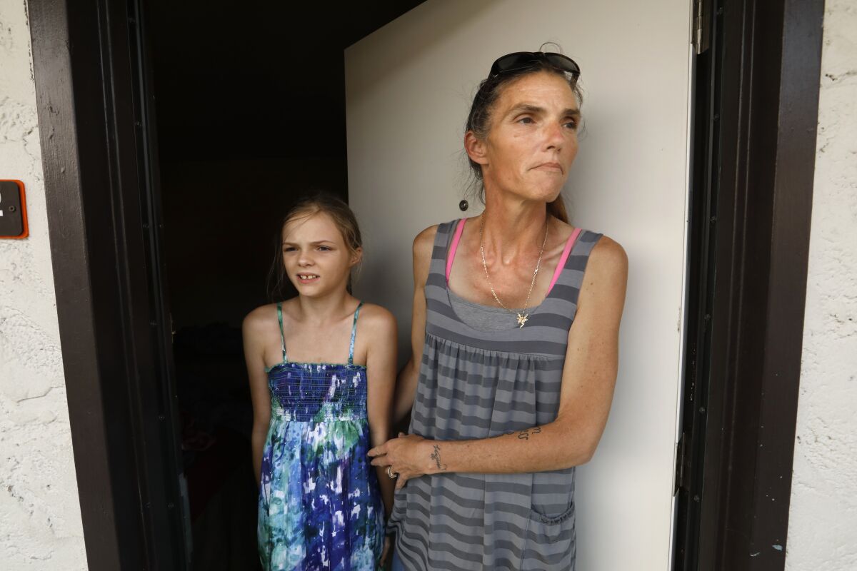 A woman and her daughter stand in the doorway of a motel room