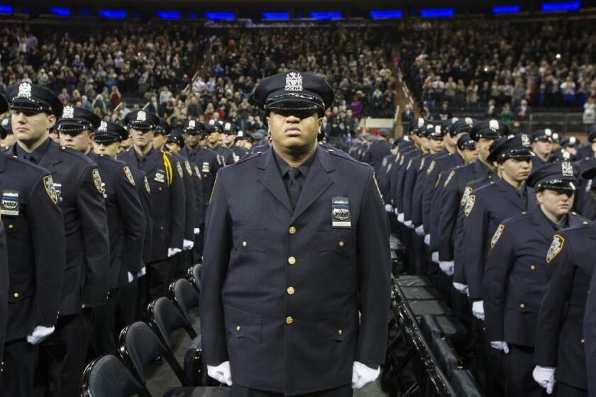 Hundreds of new NYPD recruits stand at attention at a ceremony Monday. They wore black bands over their badges in honor of officers Rafael Ramos and Wenjian Liu, who were slain Dec. 20 by a gunman who had posted anti-police rants online.