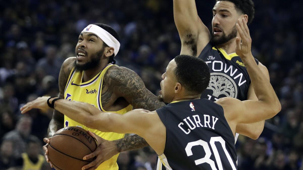 Lakers' Brandon Ingram, left, drives the ball past Golden State Warriors' Stephen Curry (30) and Klay Thompson in the first half on Saturday in Oakland.