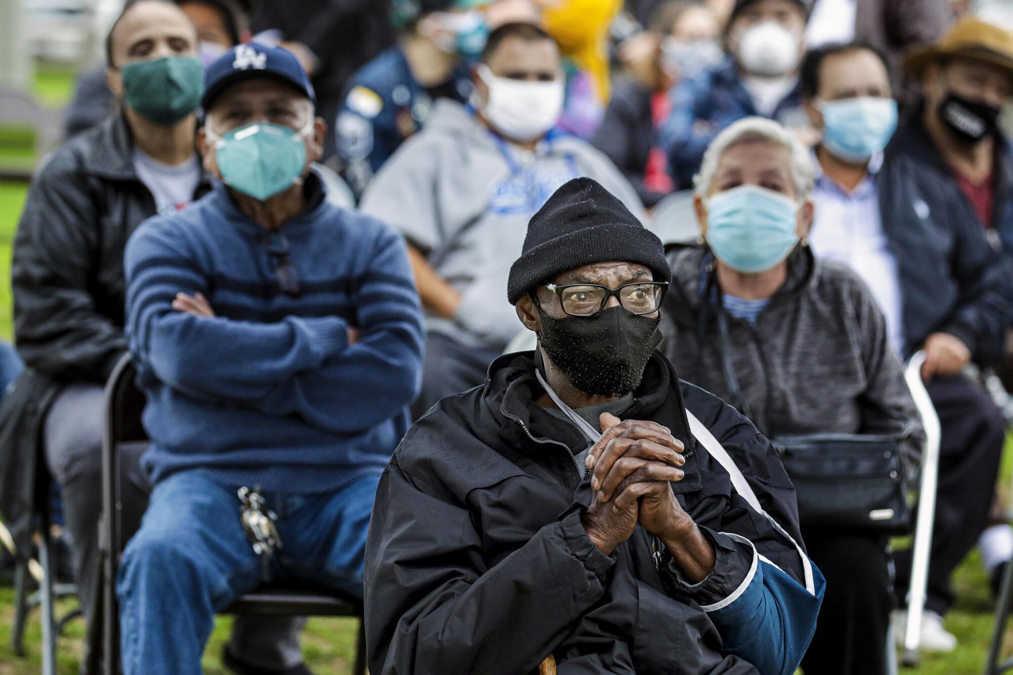 Anthony Angulo, 71, center, waits to get a COVID-19 vaccine shot.