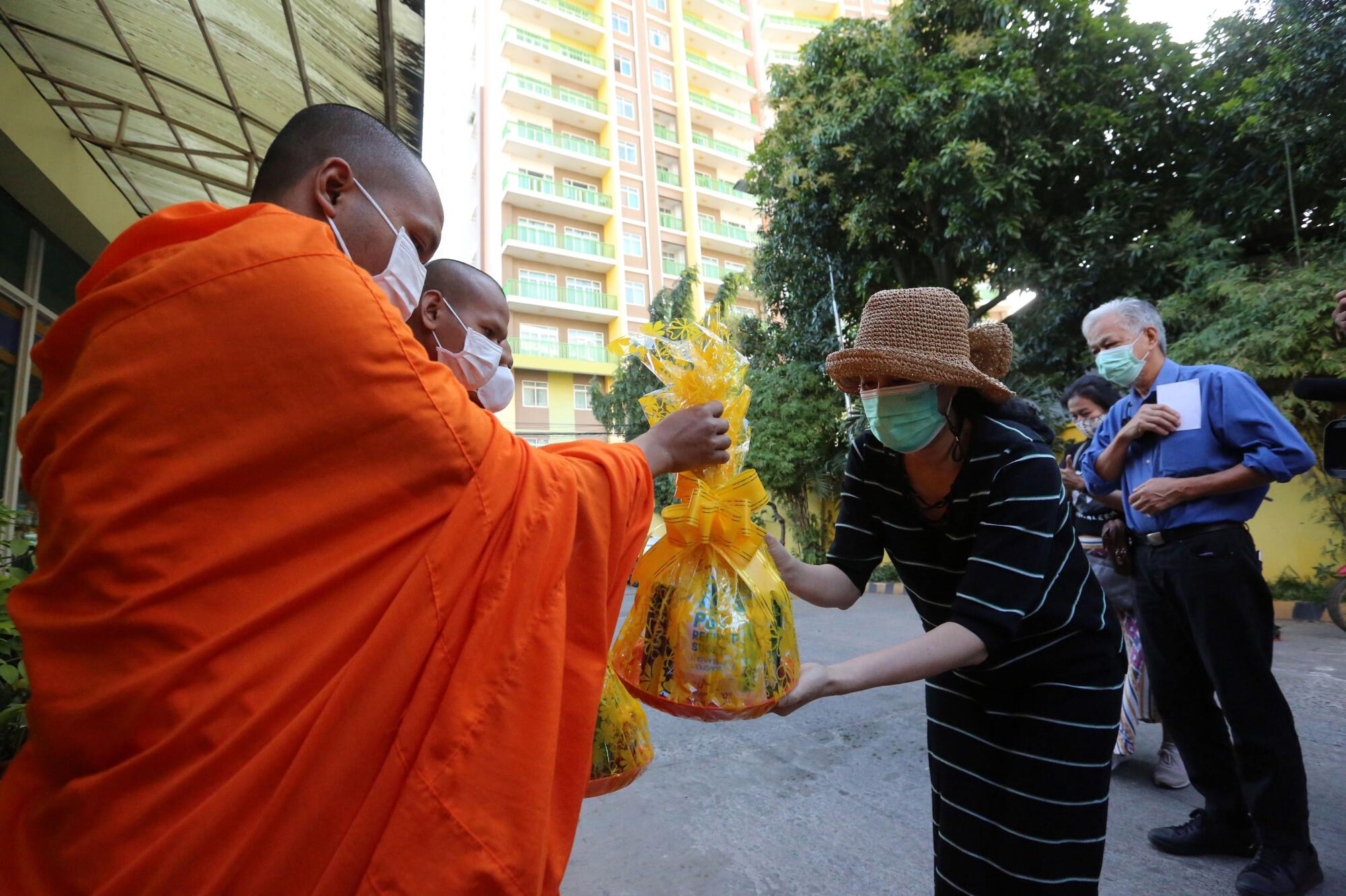 Sitanan Satsaksit hands an offering to a monk at the site of her brother's disappearance