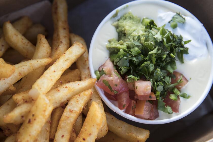 LOS ANGELES, CALIF. -- WEDNESDAY, NOVEMBER 29, 2017: 'The Abbot Kinney' white queso with jalapeno, house pico, house guacamole, sour cream and cilantro, served up with fries at Beaux Hebert's Queso truck parked across from LACMA on Wilshire Blvd. in Los Angeles, Calif., on Nov. 29, 2017. (Brian van der Brug / Los Angeles Times)