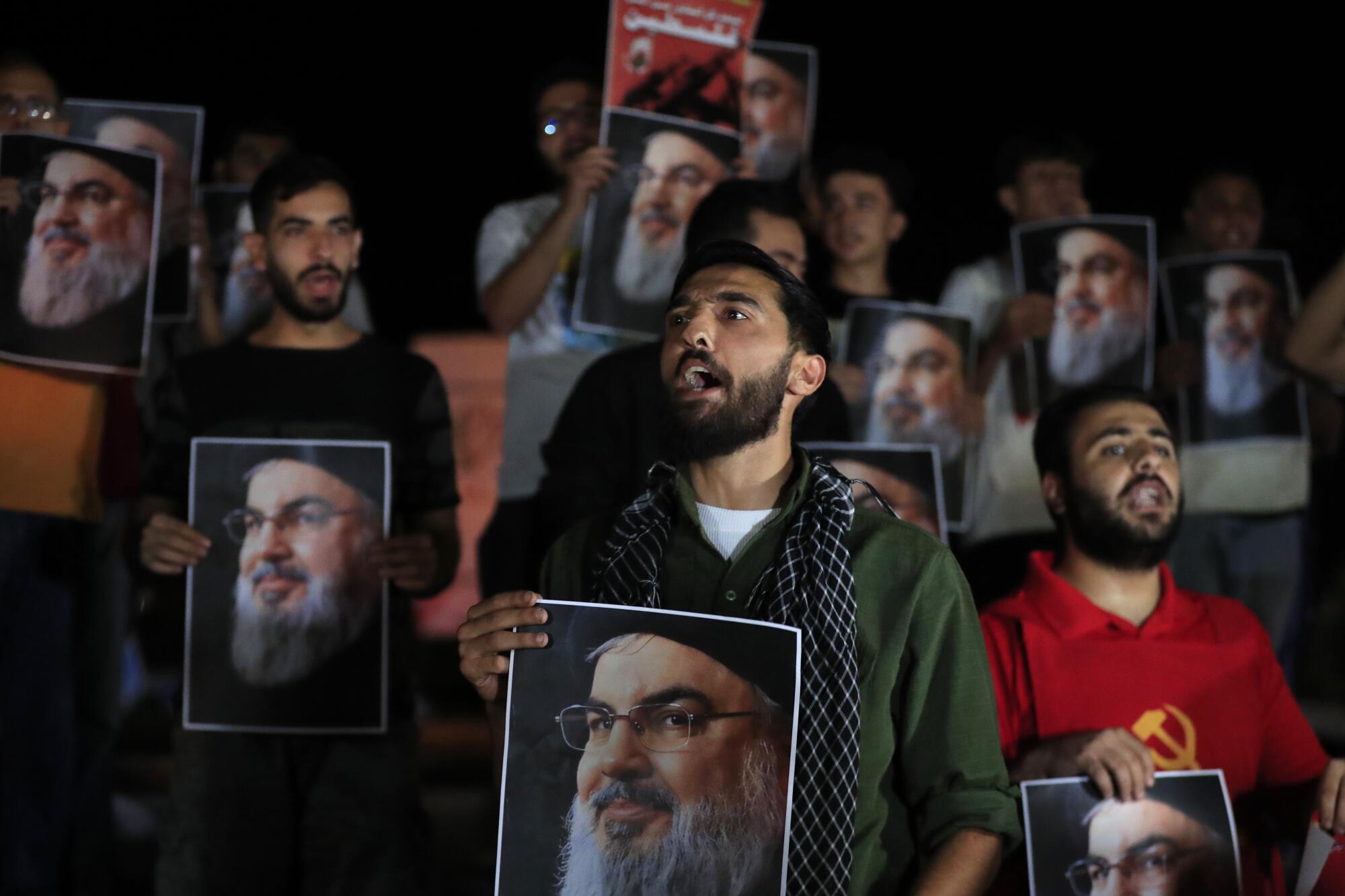 A group of men hold portraits of Hezbollah leader Hassan Nasrallah 