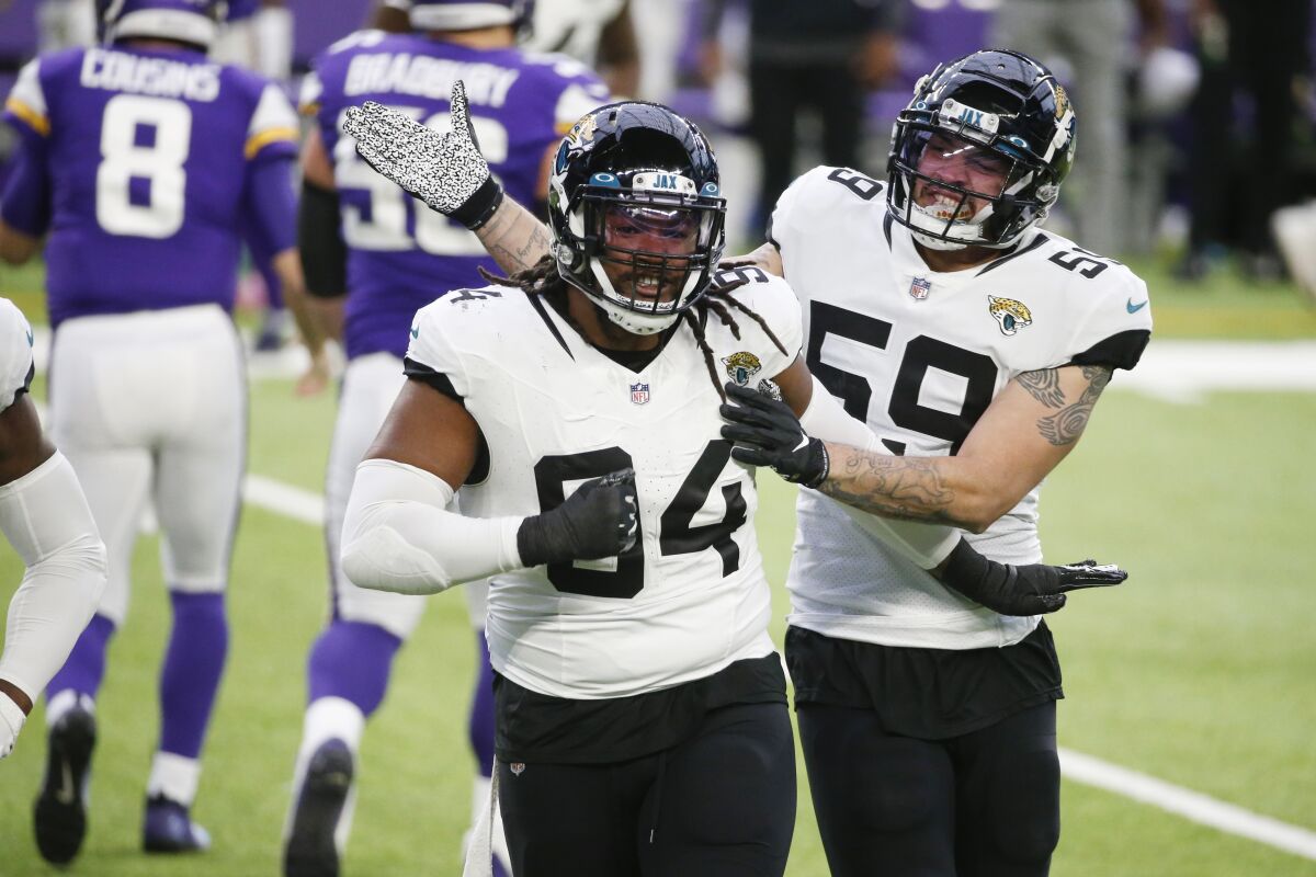 Jacksonville Jaguars defensive end Dawuane Smoot (94) celebrates with teammate Aaron Lynch (59) after a sack during the first half of an NFL football game against the Minnesota Vikings, Sunday, Dec. 6, 2020, in Minneapolis. (AP Photo/Bruce Kluckhohn)
