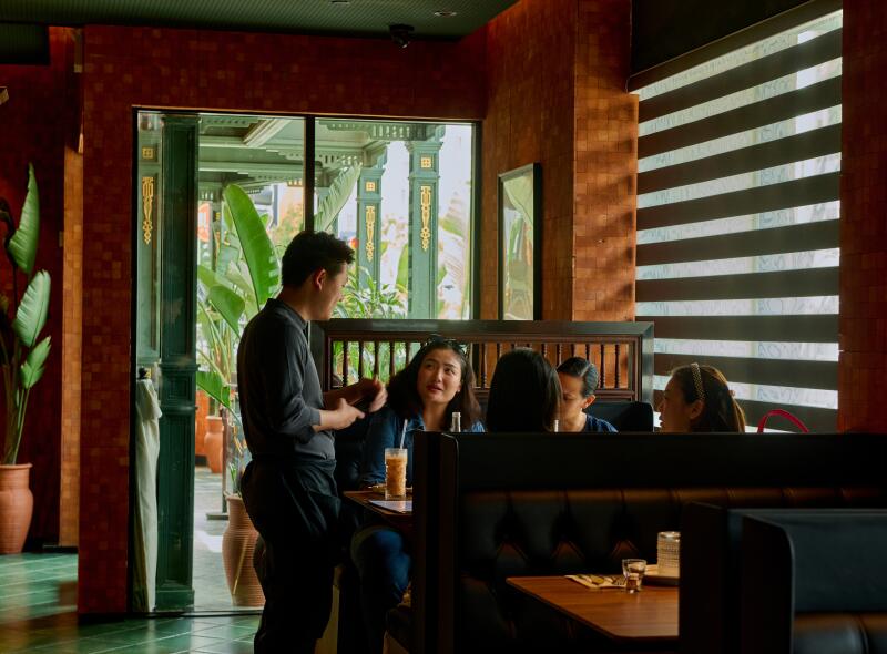 Customers place their orders inside Star Leaf, surrounded by wood-paneled walls, next to a slatted window.