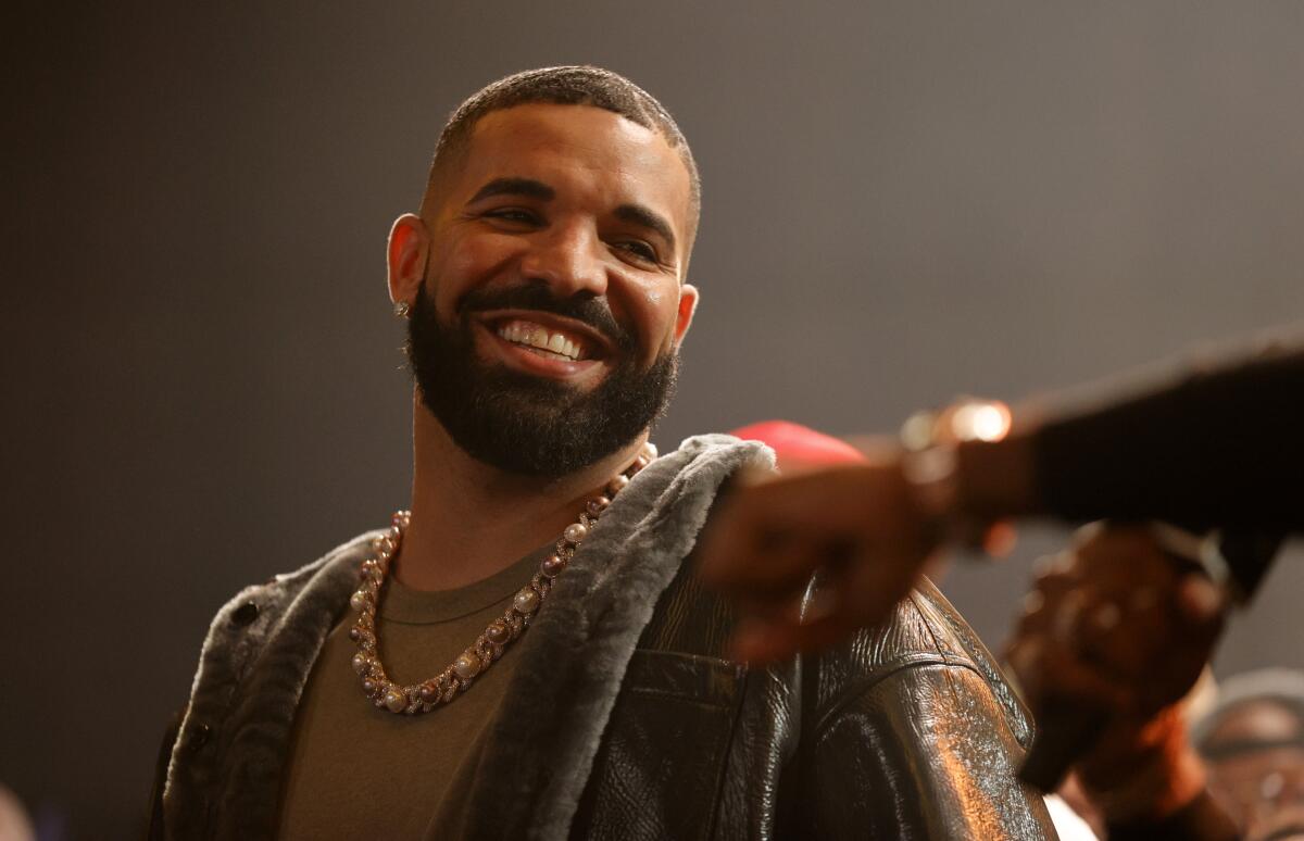 Drake smiles at a person just beyond the frame.