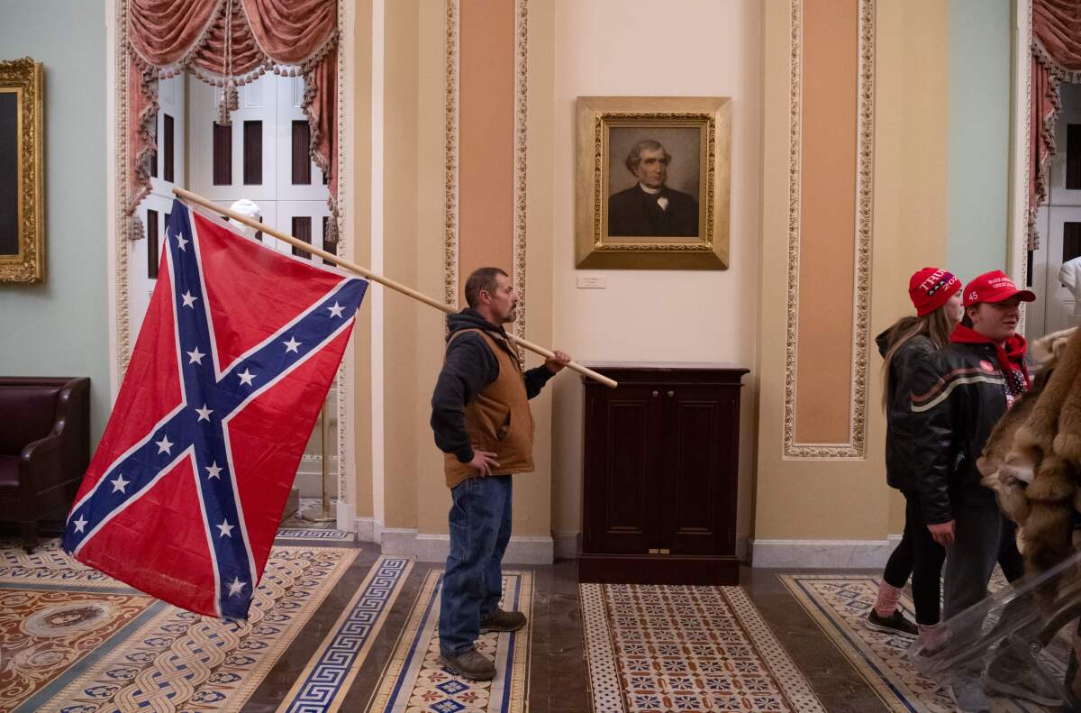 A supporter of President Donald Trump holds a Confederate flag outside the Senate Chamber.