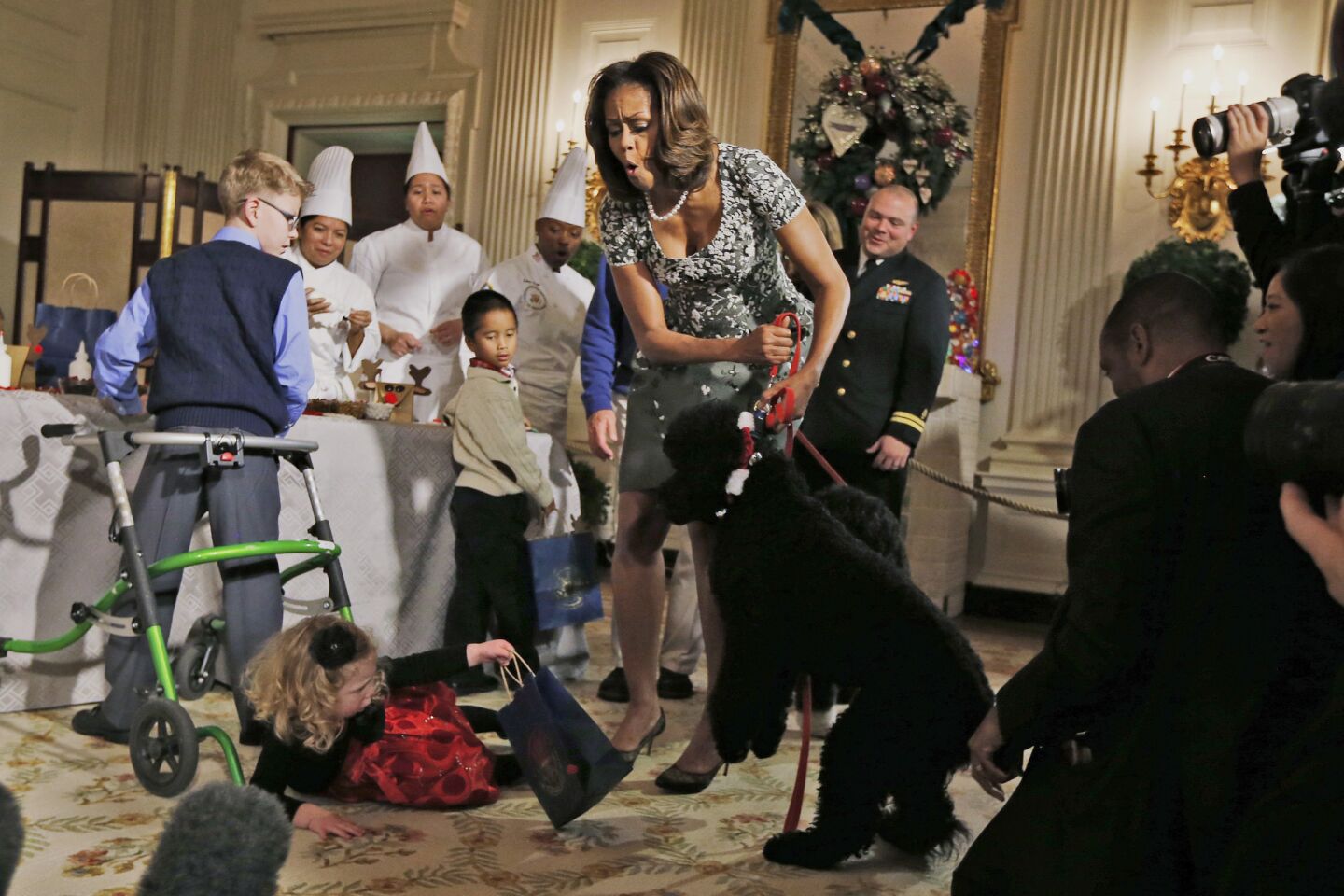 First lady Michelle Obama pulls back the family dog Sunny after Ashtyn Gardner, 2, from Mobile, Ala., lost her balance during a holiday arts and crafts event at the White House.