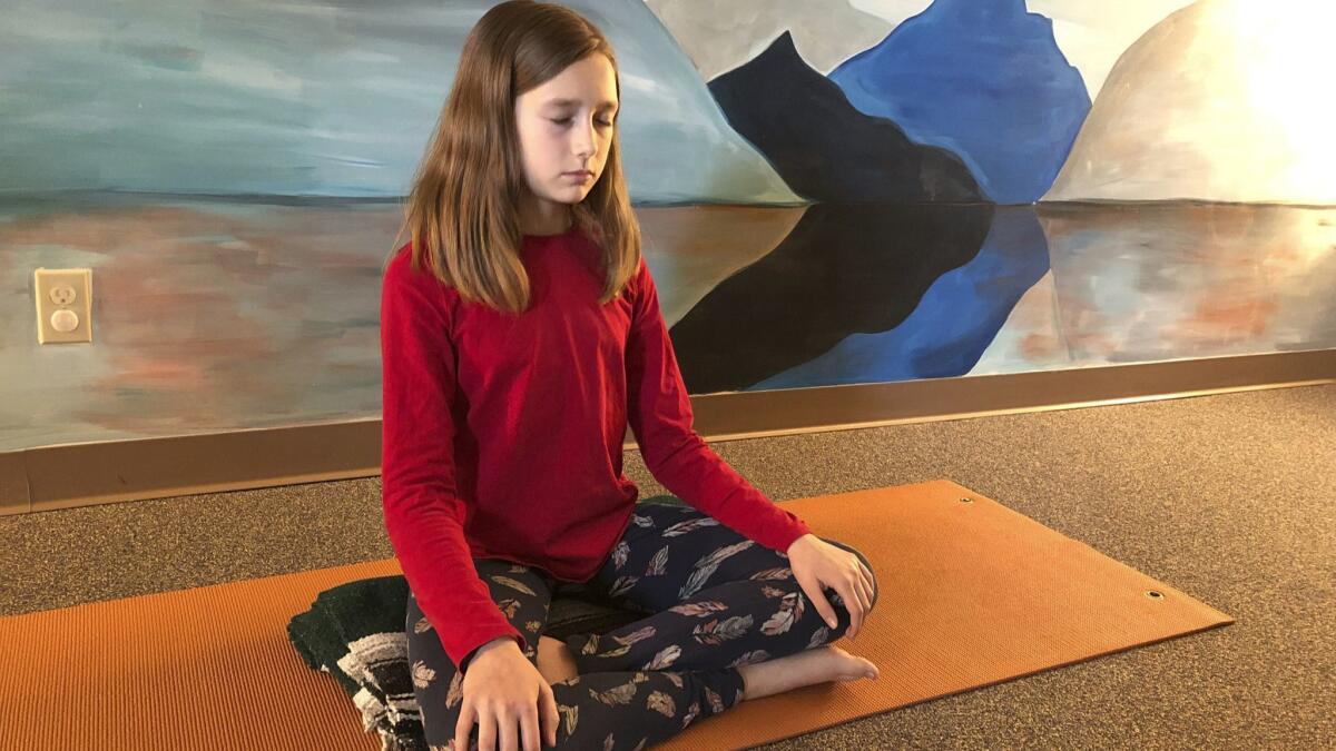 Aeva Schifferli, 12, demonstrates a stress-relieving breathing exercise at her mother's yoga studio in East Aurora, N.Y.