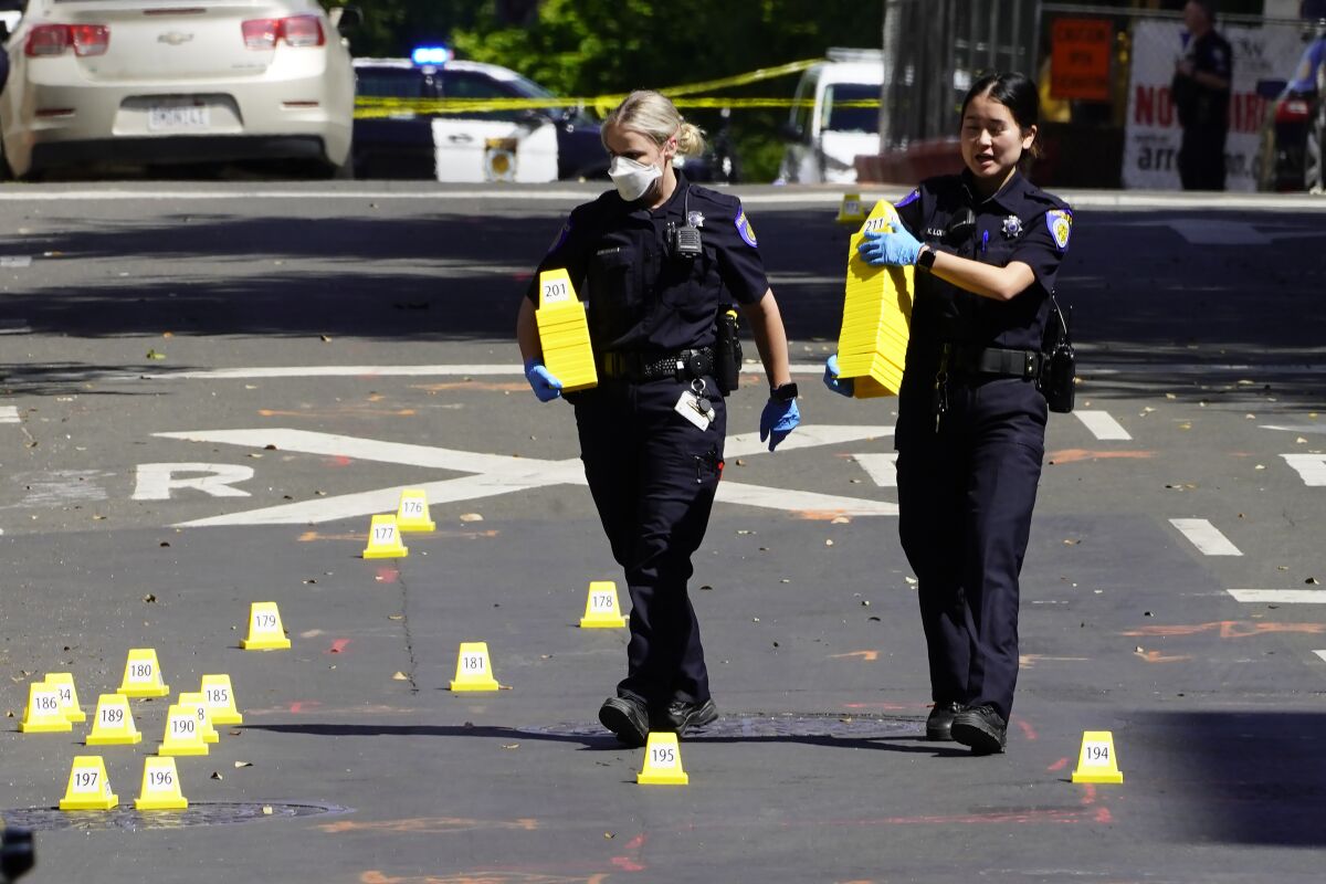 Police officers place yellow markers by shell casings