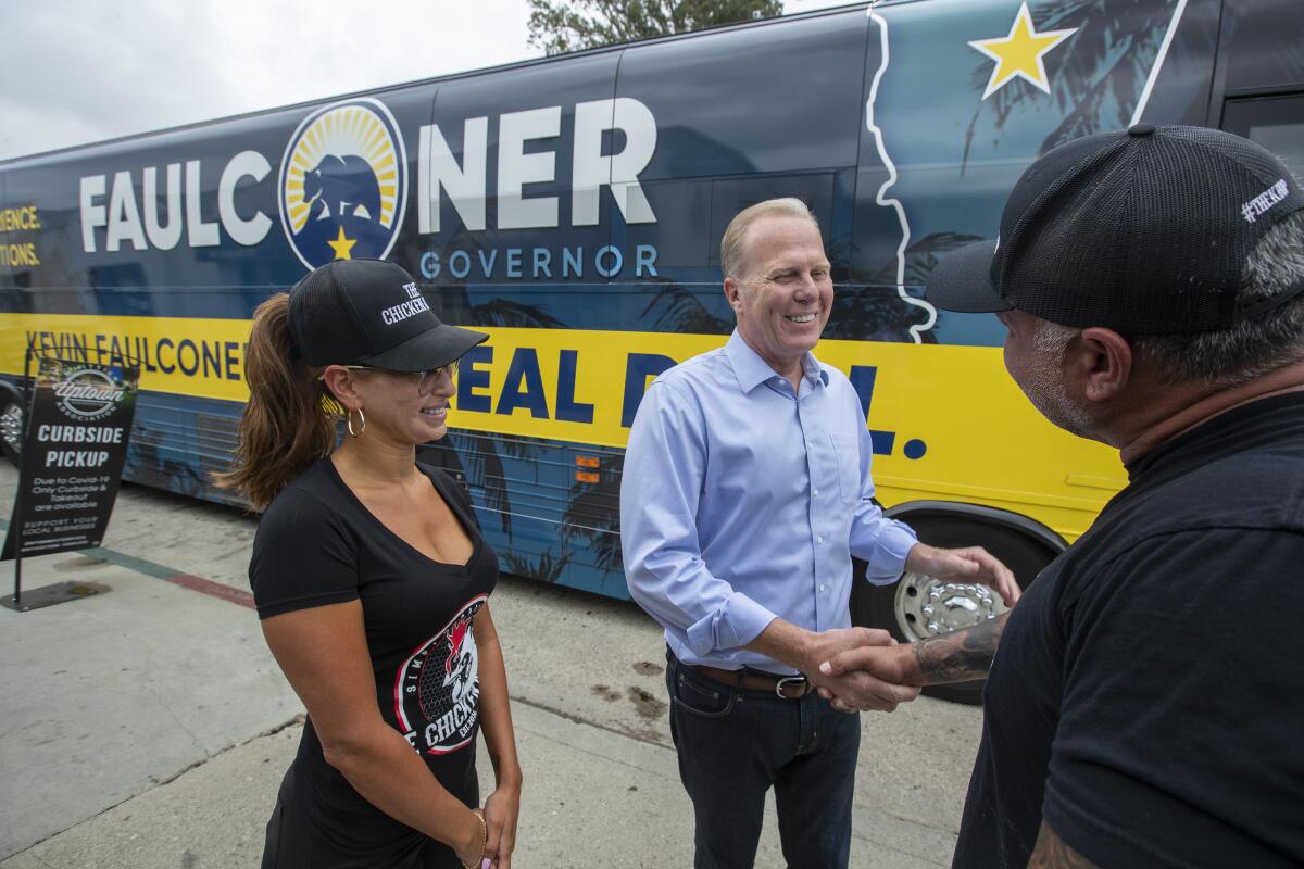 Kevin Faulconer, next to his recall campaign tour bus, shakes hands with a man.