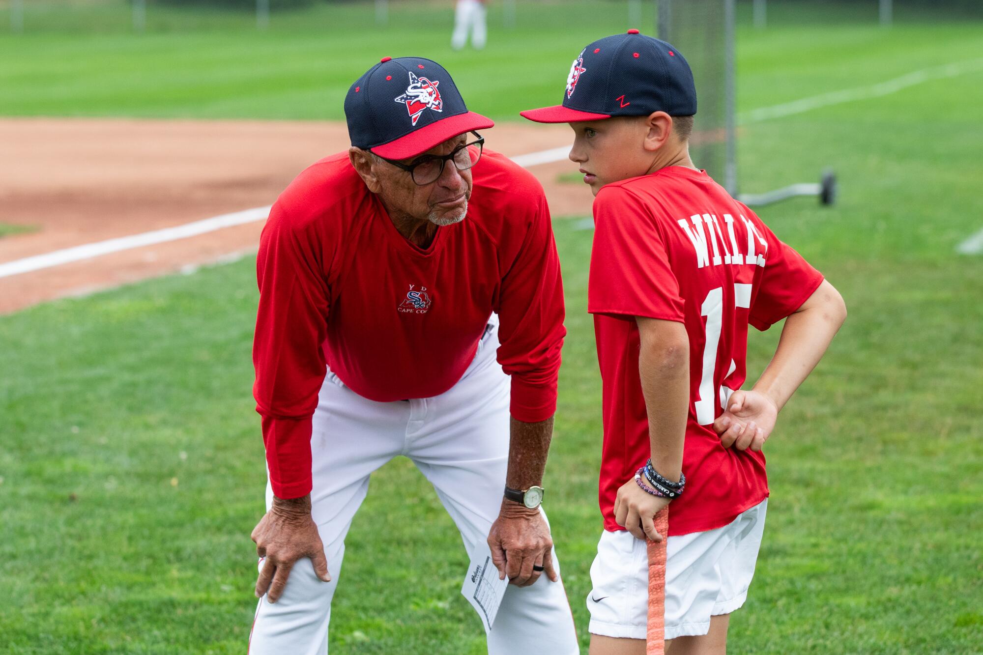 Coach Scott Pickler, left, speaks to a young baseball player.