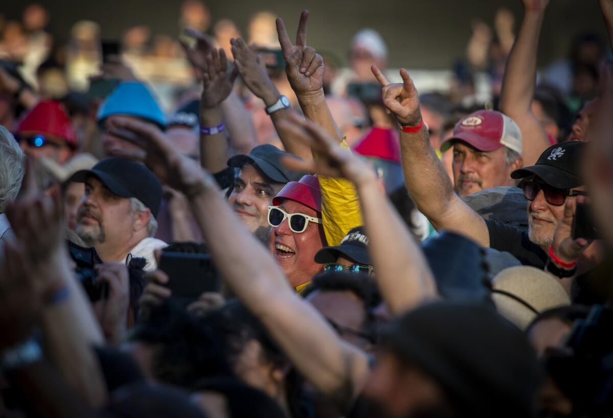 A fan wearing a Devo hat cheers in a crowd.