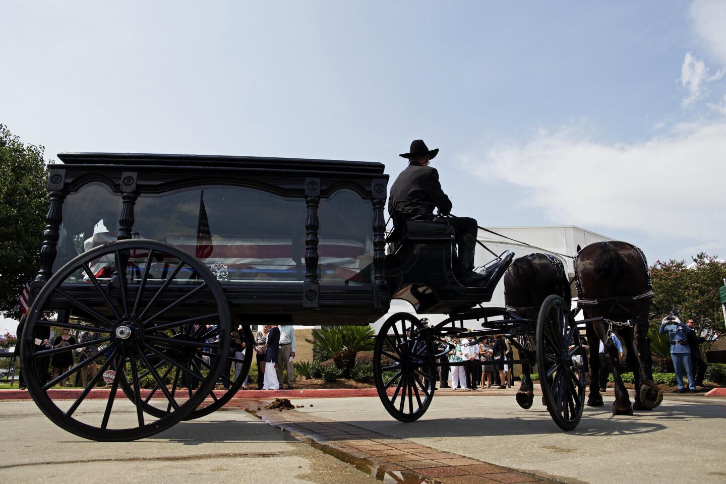 A horse-drawn carriage carries the casket of East Baton Rouge Sheriff deputy Brad Garafola at the Istrouma Baptist Church in Baton Rouge, La., on July 23, 2016.