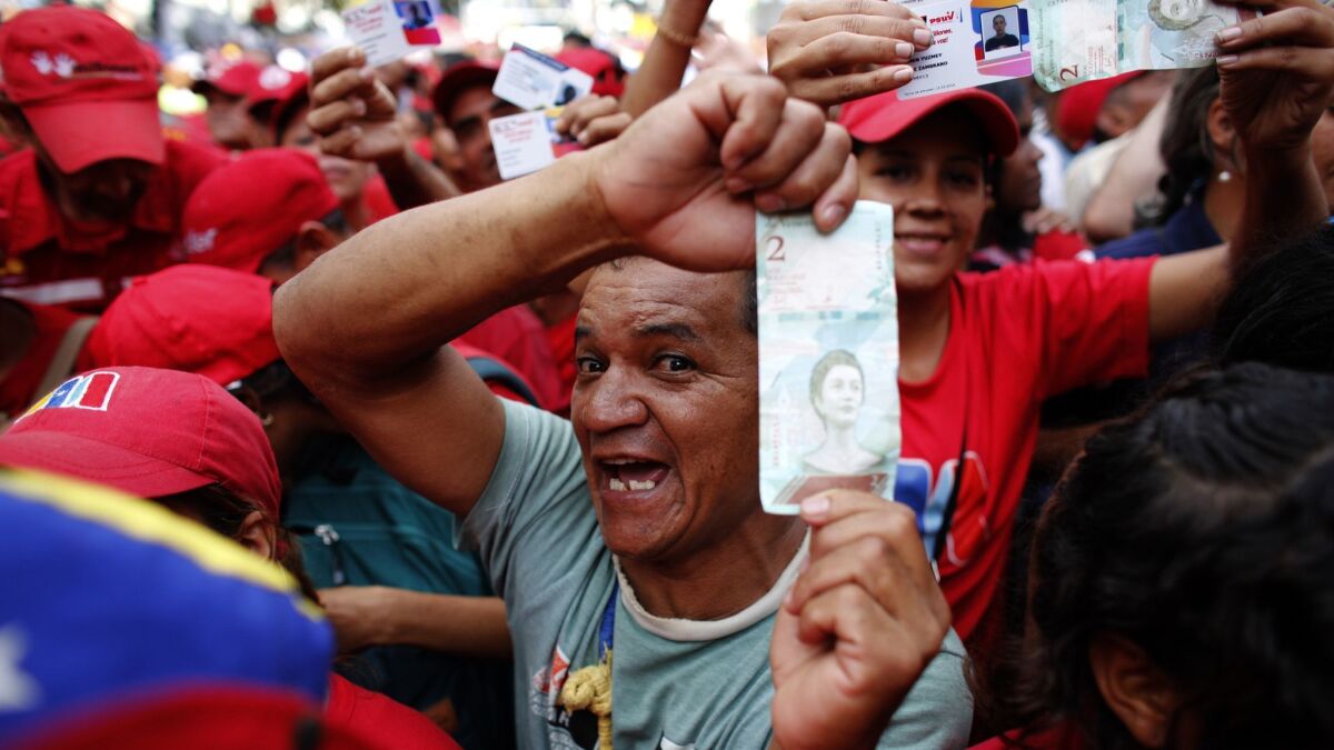 Pro-government supporters cheer as some hold up new bank notes and patriot identification cards during a rally in Caracas, Venezuela's capital, on Aug. 21, 2018. Others predicted more hardship ahead.
