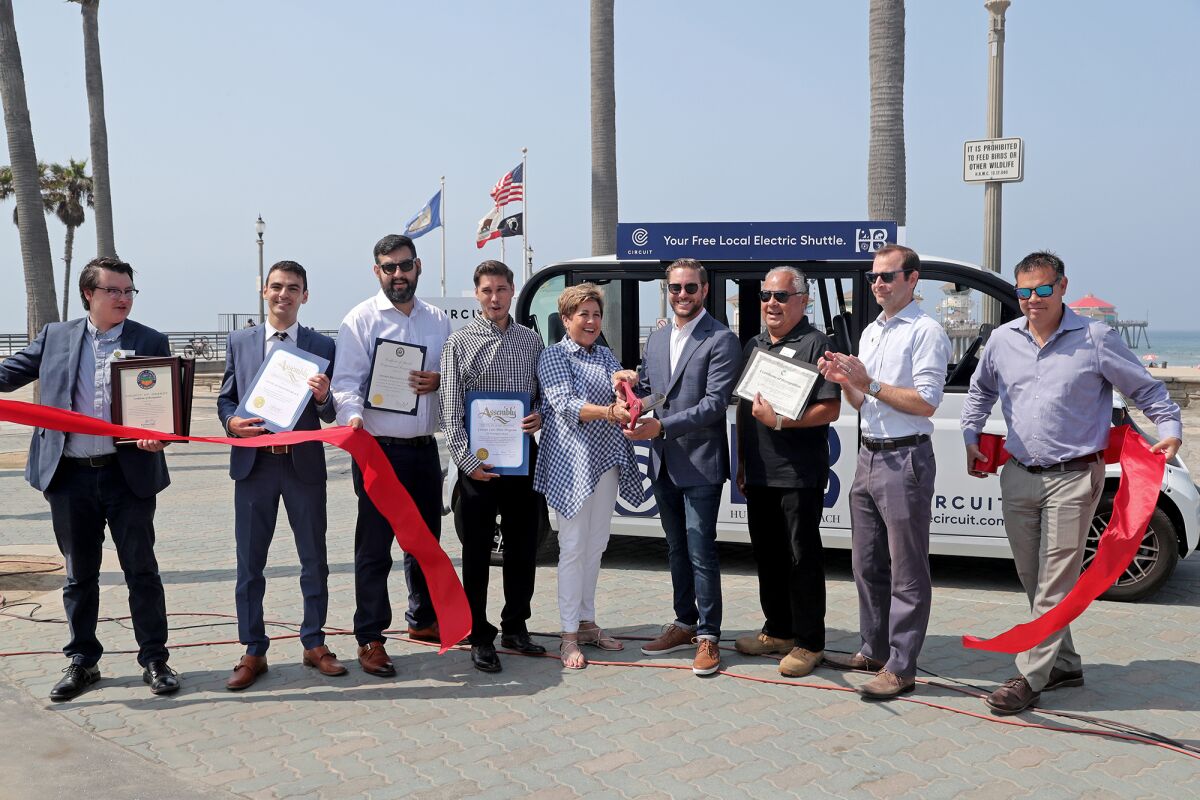 Huntington Beach Mayor Pro Tem Barbara Delgleize, center, and Daniel Kramer with Circuit Cars, cut the ceremonial ribbon.
