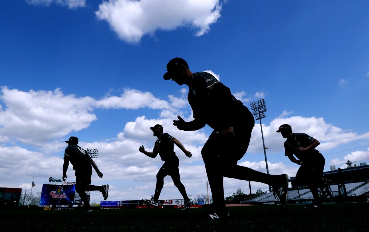 FILE - Quad Cities River Bandits players warm up before a Class-A Midwest League baseball game against the Cedar Rapids Kernels in Cedar Rapids, Iowa, Monday, May 13, 2019. Minor league players and Major League Baseball have reached a settlement in a lawsuit alleging teams violated minimum wage laws. The settlement has not yet been filed with the court and details were not released Tuesday, May 10, 2022. (AP Photo/Charlie Neibergall, File)