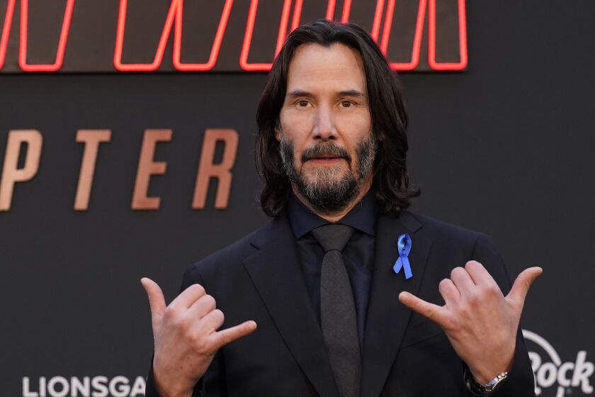 Keanu Reeves makes shaka indicators with his hands at a movie premiere  T&#8217;fina Pkaila With Purple meat  url https 3A 2F 2Fcalifornia times brightspot