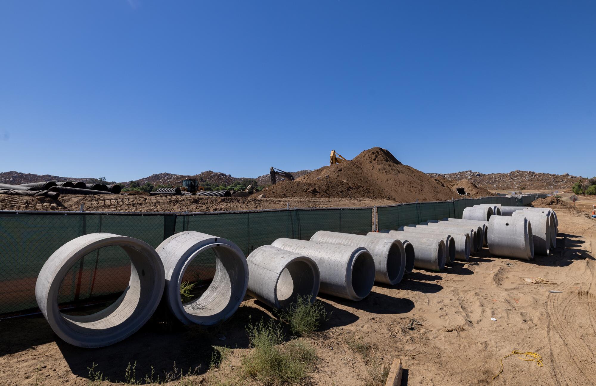 Concrete pipe sections sit side-by-side at a construction site. 