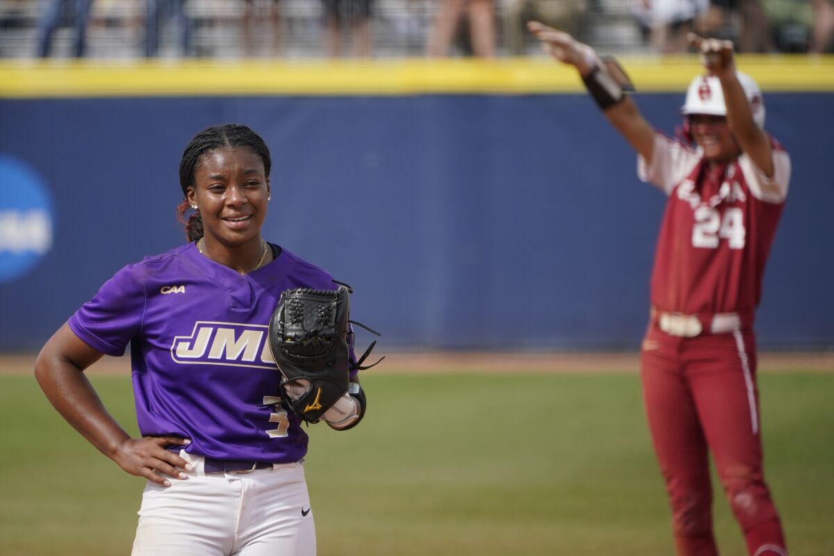 James Madison pitcher Odicci Alexander stands in the pitching circle as Oklahoma's Jayda Coleman celebrates.