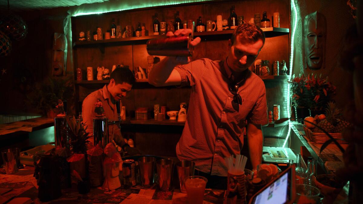 PDT bartenders Christian Hurtado, left, and Adam Schmidt work behind the bar at PDTiki at the Coachella festival.