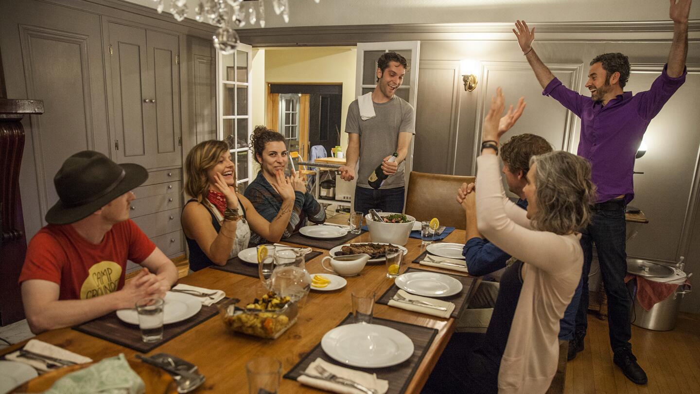 Jay Standish, center, cofounder of OpenDoor, opens a bottle of Champagne on Feb. 28 to celebrate the first group dinner with his new housemates at one of the company's co-living homes in Oakland.