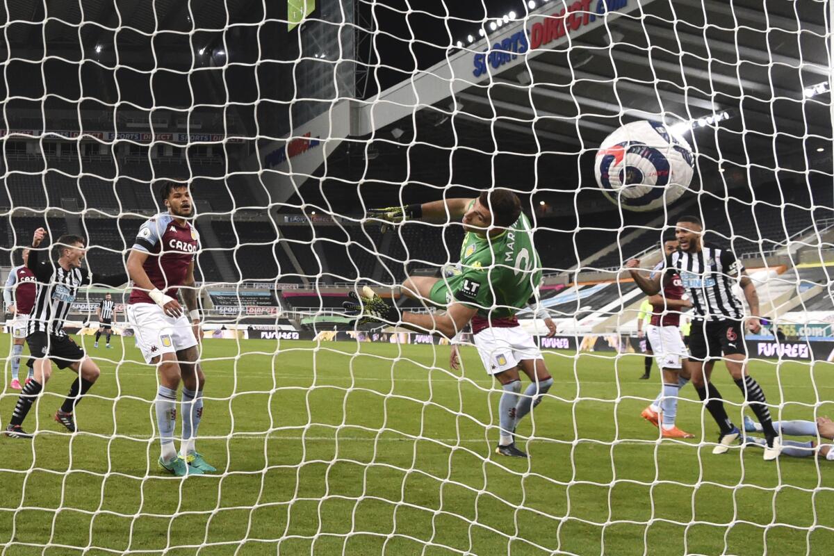 Aston Villa's goalkeeper Emiliano Martinez fails to save the goal from Newcastle's Jamaal Lascelles, right, during the English Premier League soccer match between Newcastle United and Aston Villa at the St James' Park stadium in Newcastle, England, Friday, March 12, 2021. (Stu Forster/Pool via AP)