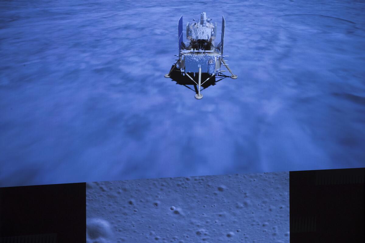 A display screen in Beijing shows the China's Chang'e-5 spacecraft and an image of the moon's surface taken by the craft