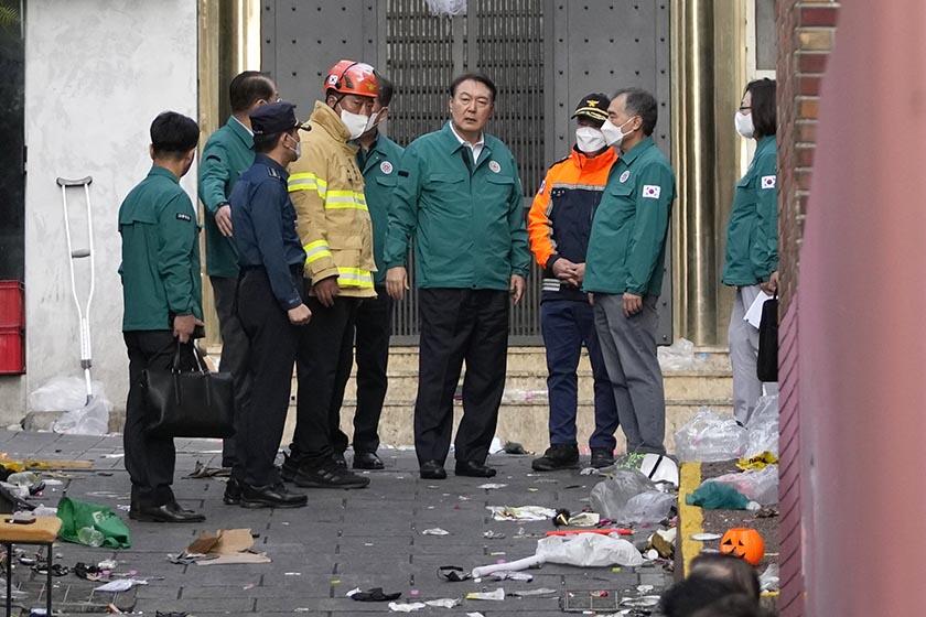 South Korean President Yoon Suk Yeol, center, visits an alley in Seoul where dozens of people died in a crowd surge.