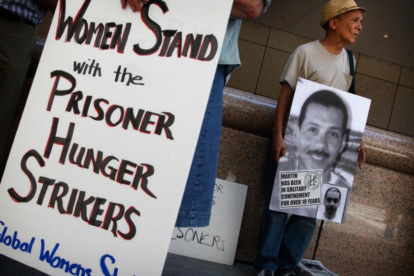 John A. Imani, right, joins about 75 demonstrators Monday in front of the Ronald Reagan State Building in Los Angeles for a rally held in support of Pelican Bay State Prison inmates who are refusing meals in protest of conditions at the prison.