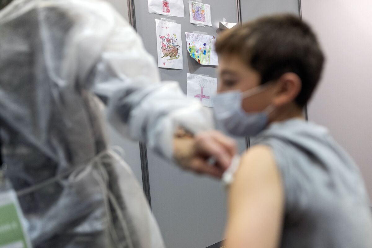 Kids drawings hang on a wall as a boy is vaccinated, in a vaccination center, in Nantes, western France, Thursday, Dec. 30, 2021. France has vaccinated 77% of its population and is rushing out booster shots. But more than 4 million adults remain unvaccinated. (AP Photo/Jeremias Gonzales)