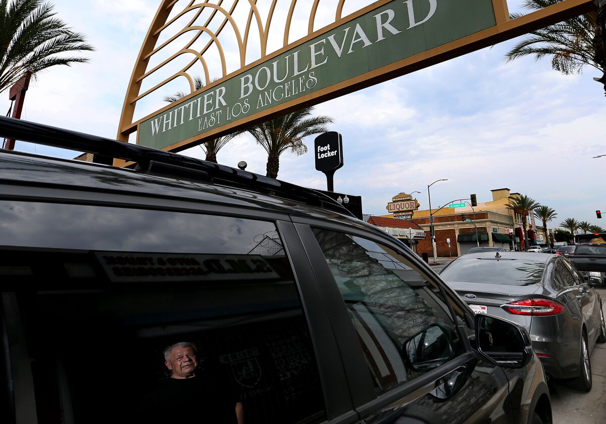 Frank Villalobos is reflected on the window of a car making its way along Whittier Boulevard in East L.A.