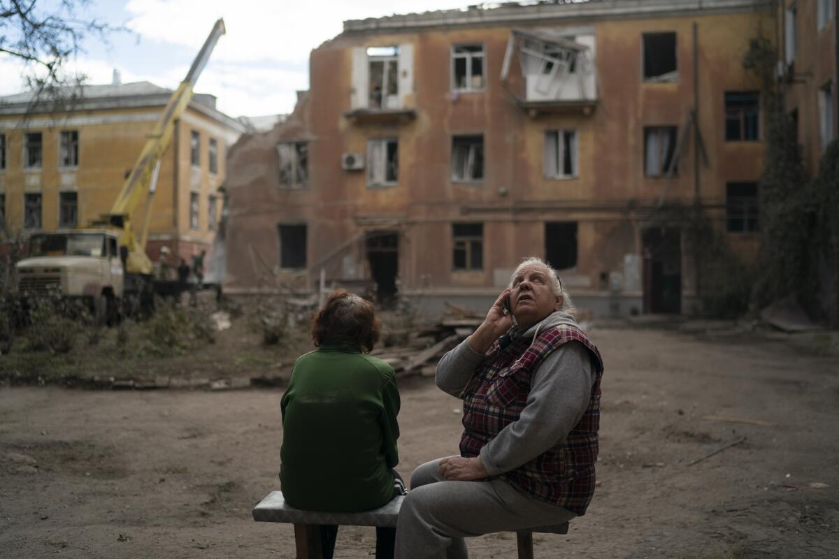 Raisa Smielkova looks up as she sits in front of the site where firefighters work to extinguish a fire.