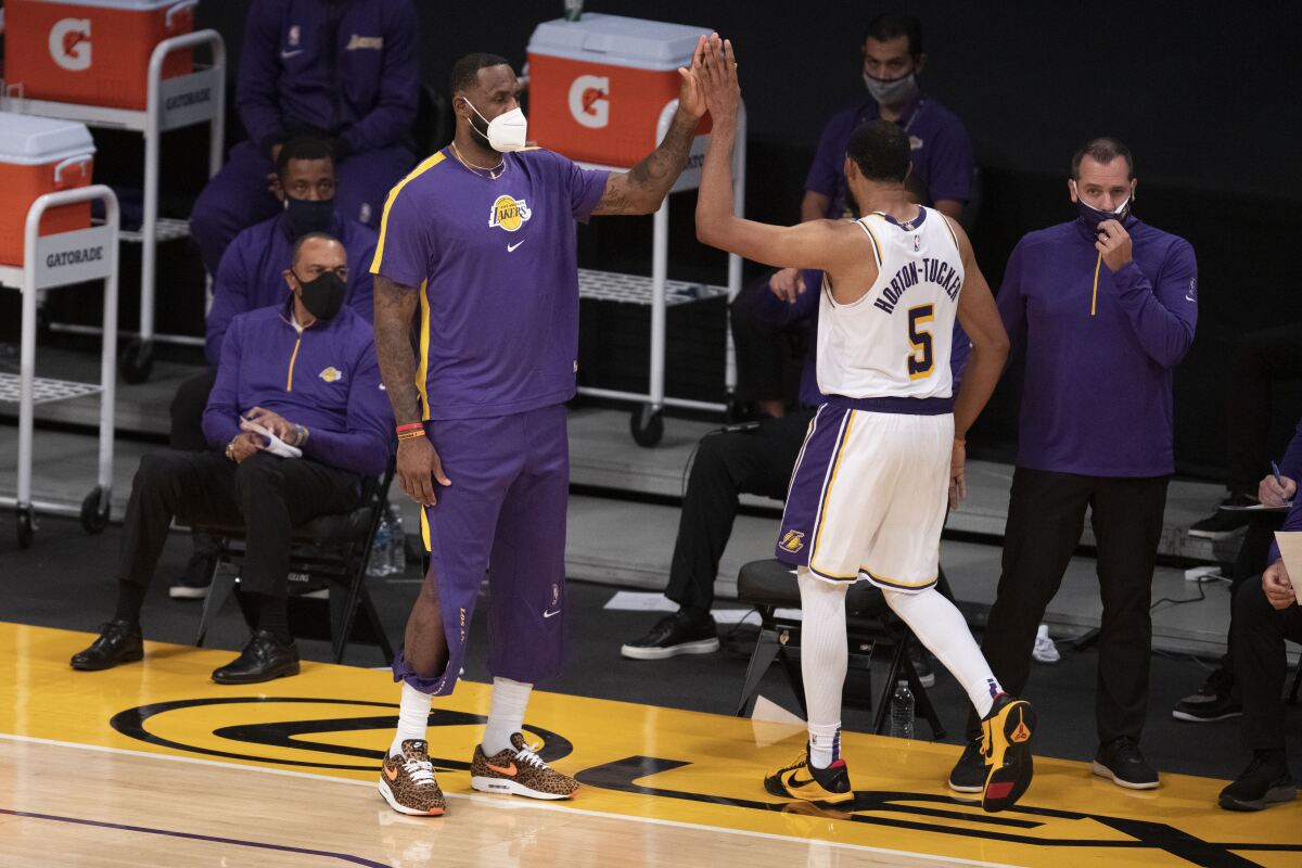 Lakers forward LeBron James greets guard Talen Horton-Tucker on the sideline while sitting out a preseason game.