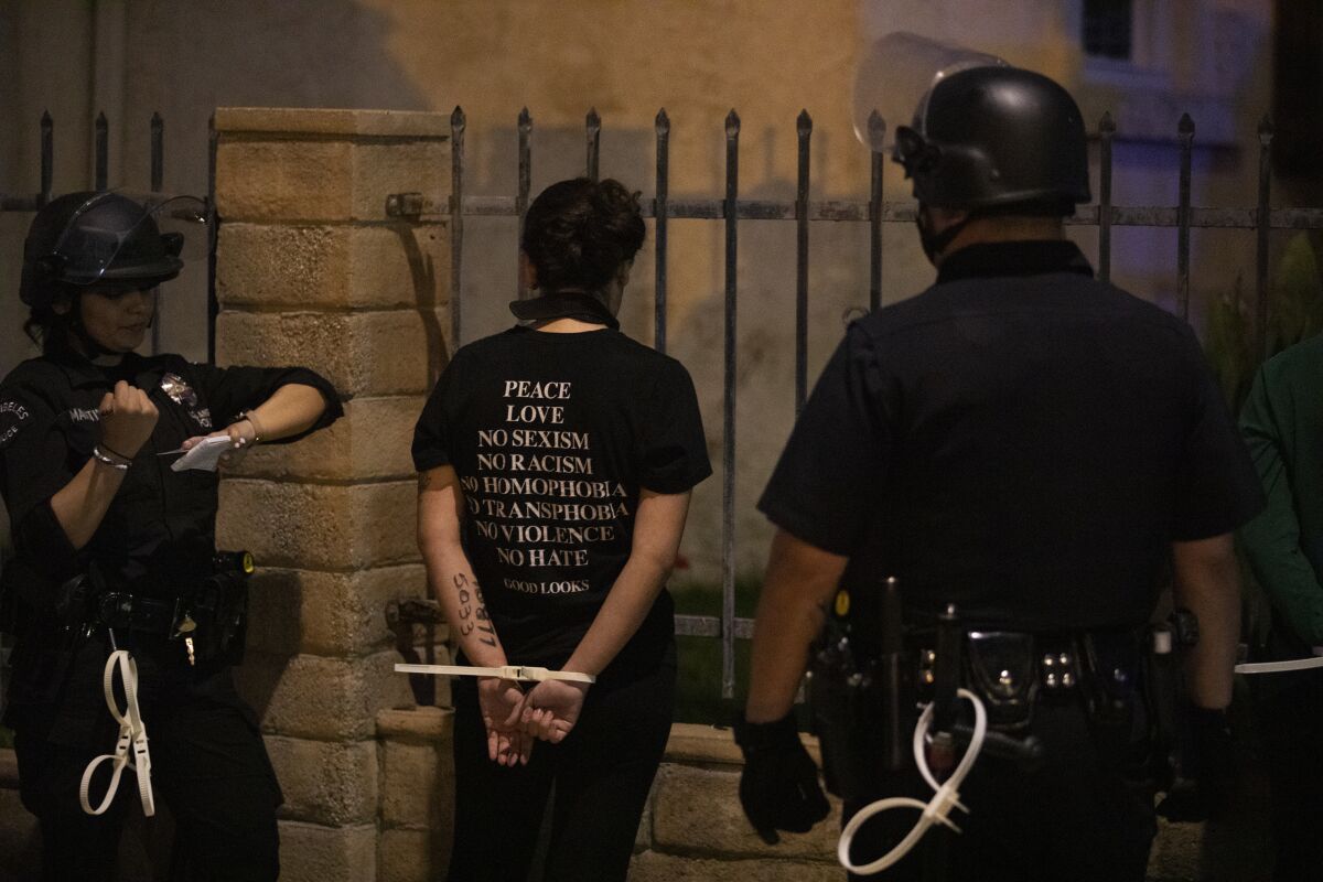 Police in Los Angeles put a protester in plastic handcuffs for curfew violation after a day of peaceful protest