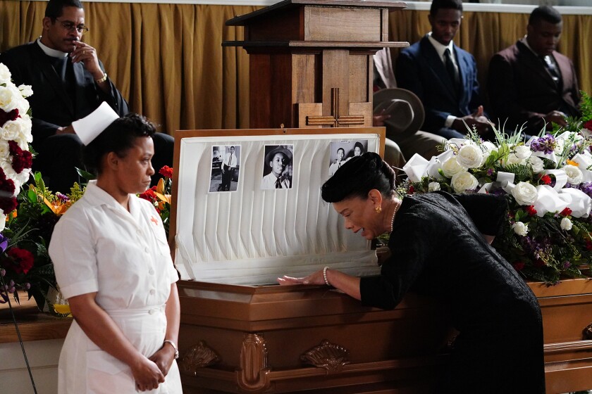 A woman cries as she looks into an open casket during a funeral.