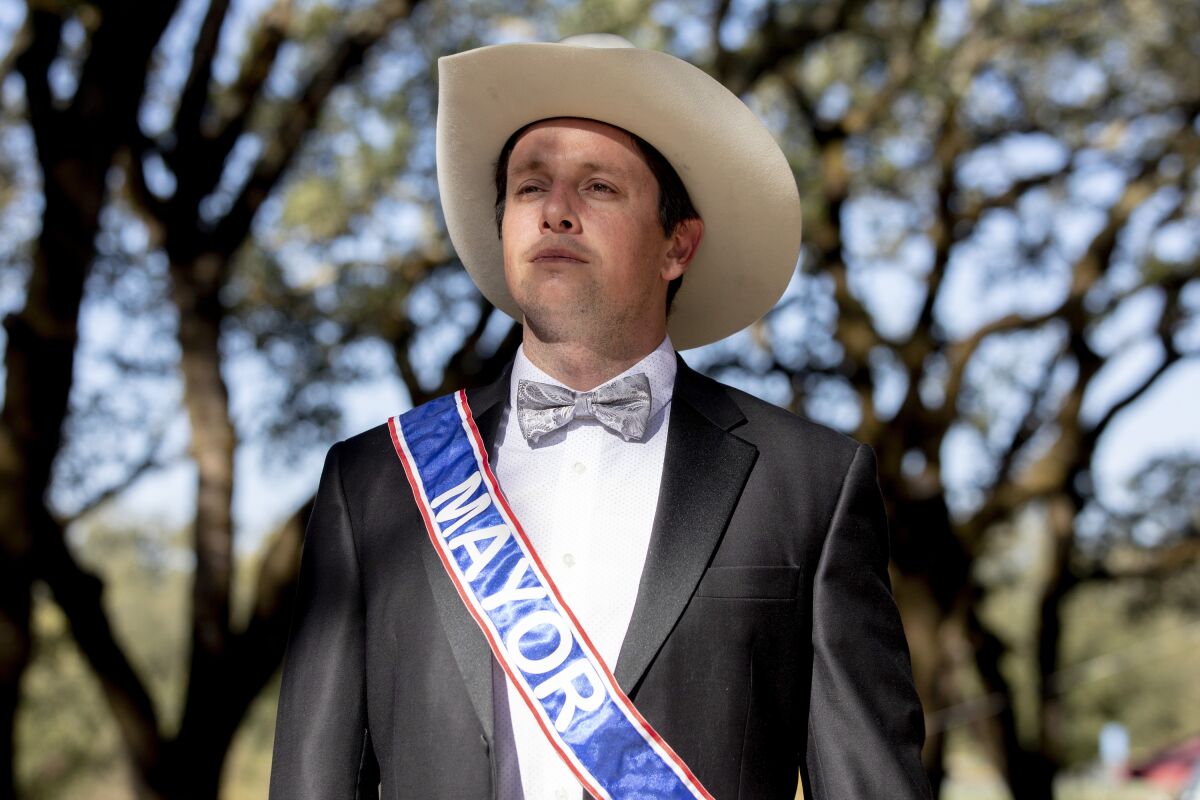 Dominic Foppoli wears a suit with bow tie and a sash reading "Mayor."