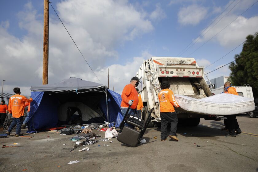 SAN DIEGO, CA - FEBRUARY 1: Workers for the Alpha Project and the city of San Diego removed homeless encampments on Sports Arena Blvd. on Tuesday, Feb. 1, 2022 in San Diego, CA. Many of the homeless people moved their belongings across the street while others had their belongings hauled away. (K.C. Alfred / The San Diego Union-Tribune)