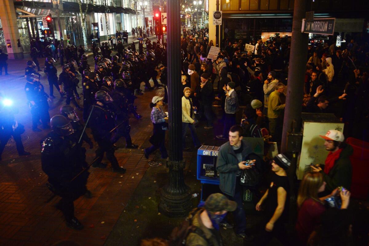 Police wearing riot gear watch as demonstrators protest against Donald Trump in Portland