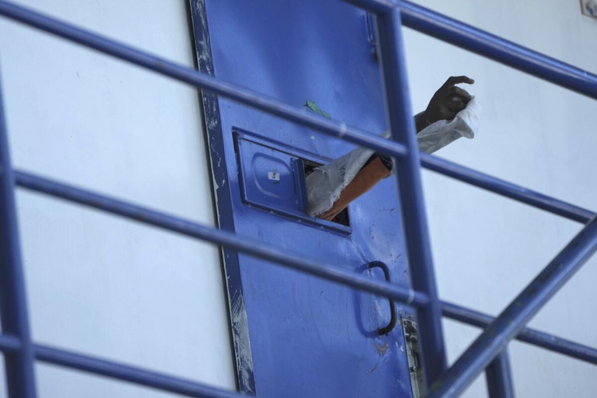 Un reo saca su brazo a través de la puerta de su celda en la cárcel de Cotopaxi, mientras los militares 