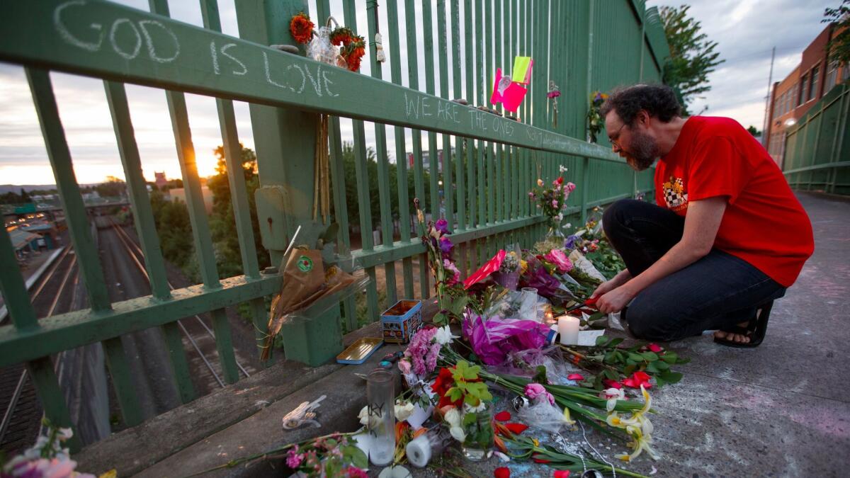 Ian Osgood lights a candle at the growing memorial at Hollywood TriMet MAX train station in Portland, June 1, 2017, near where last week three men were stabbed after an man yelled anti-Muslim taunts at two teenagers. Two of the men died.