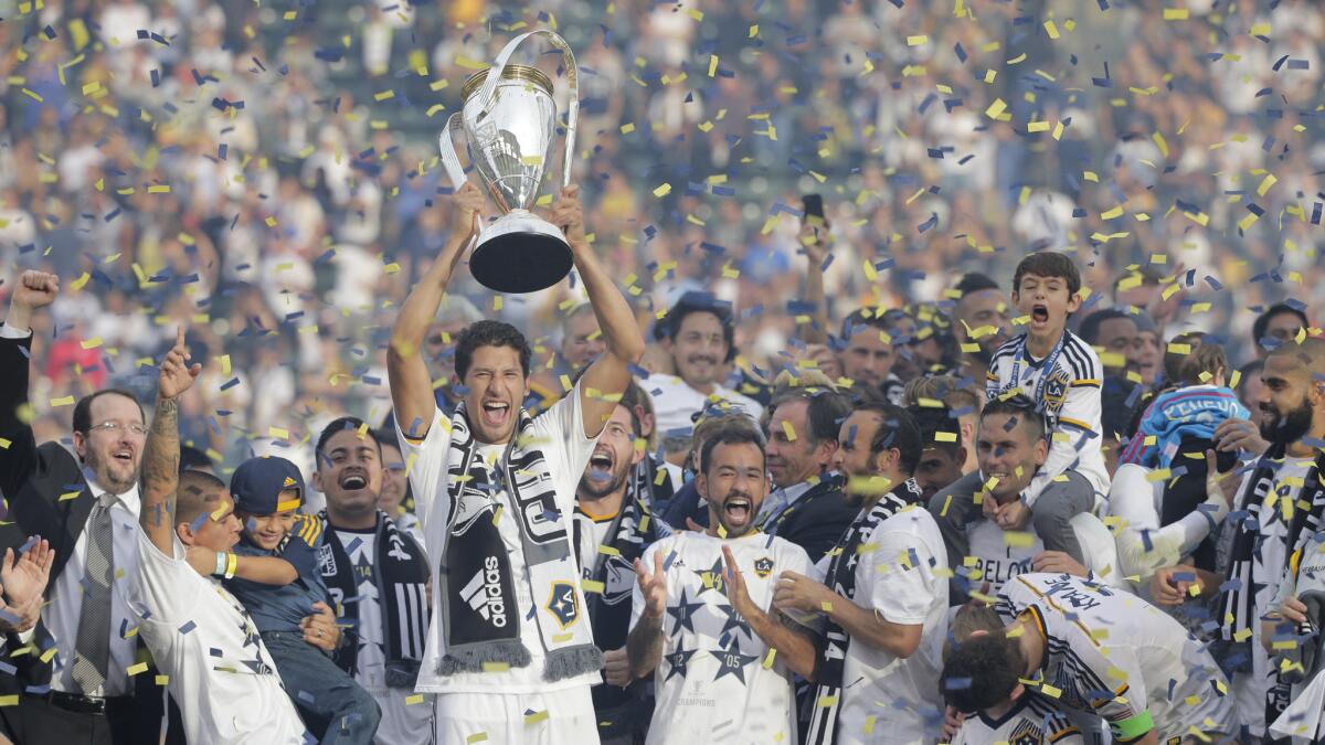 Omar Gonzalez, the Galaxy's national team defender, holds the MLS Cup trophy after a 2-1 overtime victory over the New England Revolution on Dec. 7, 2014.