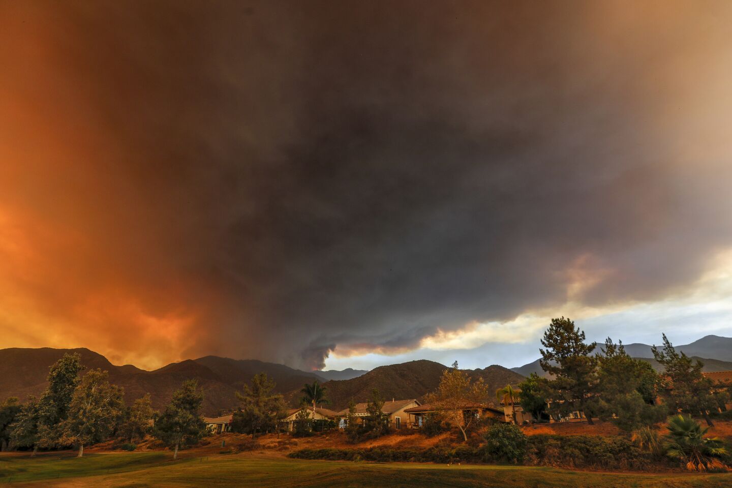 Smoke from the Holy fire darkens the sky over the Glen Ivy Golf Club as the blaze burns on the mountain ridges around Corona.