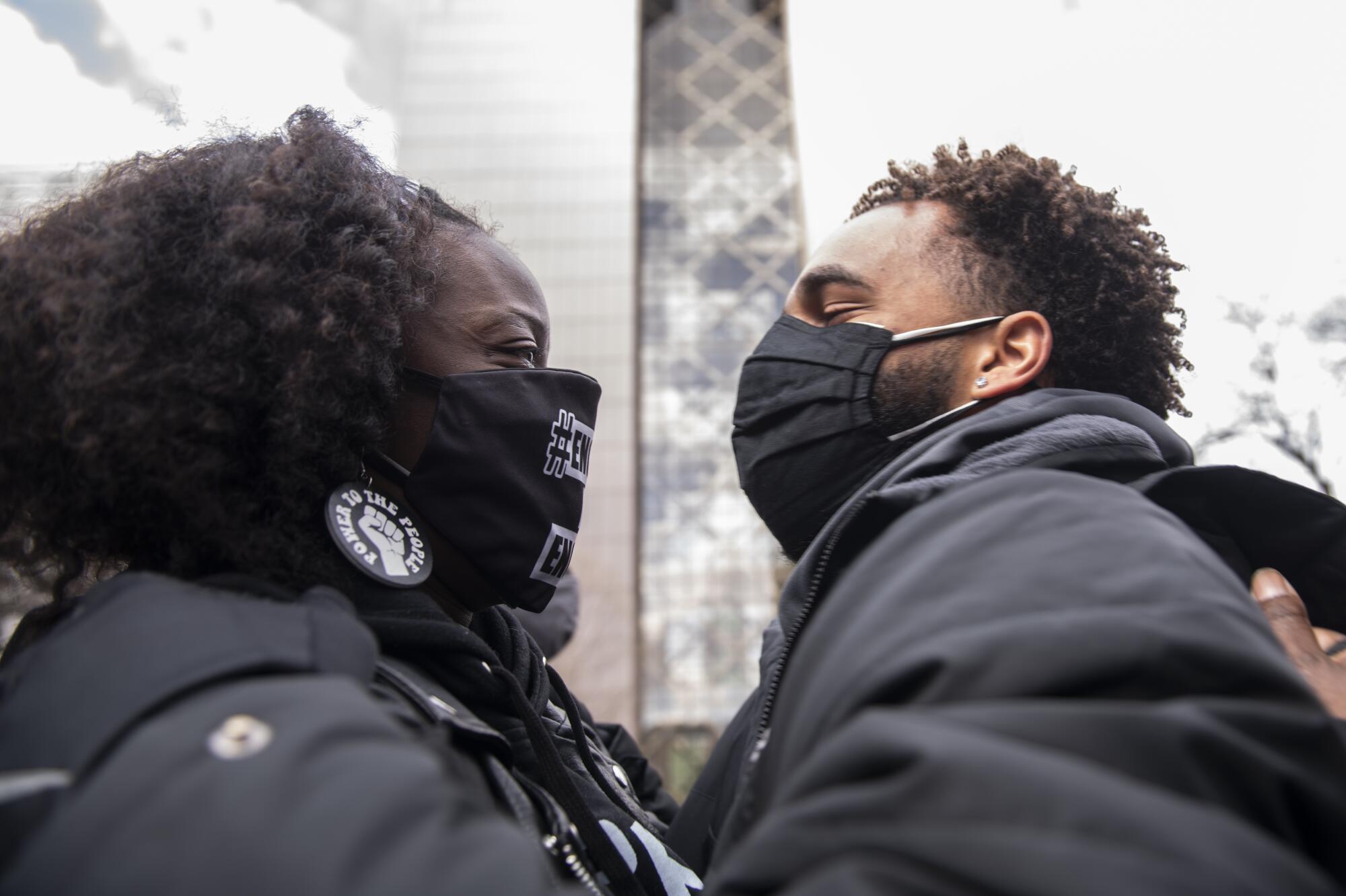 Two masked people embrace